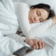 A woman is fast asleep with her smartphone next to her.