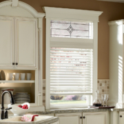A kitchen with white wooden window treatment from Lutron.