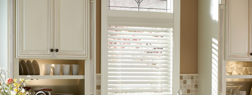 A kitchen with white wooden window treatment from Lutron.