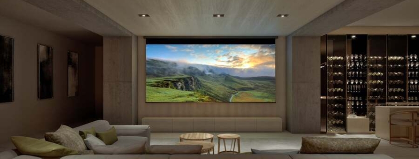 A luxurious home theater installation featuring a large screen and projector and comfy seating.