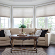 A luxury living room with Lutron motorized shades halfway down, overlooking a garden.