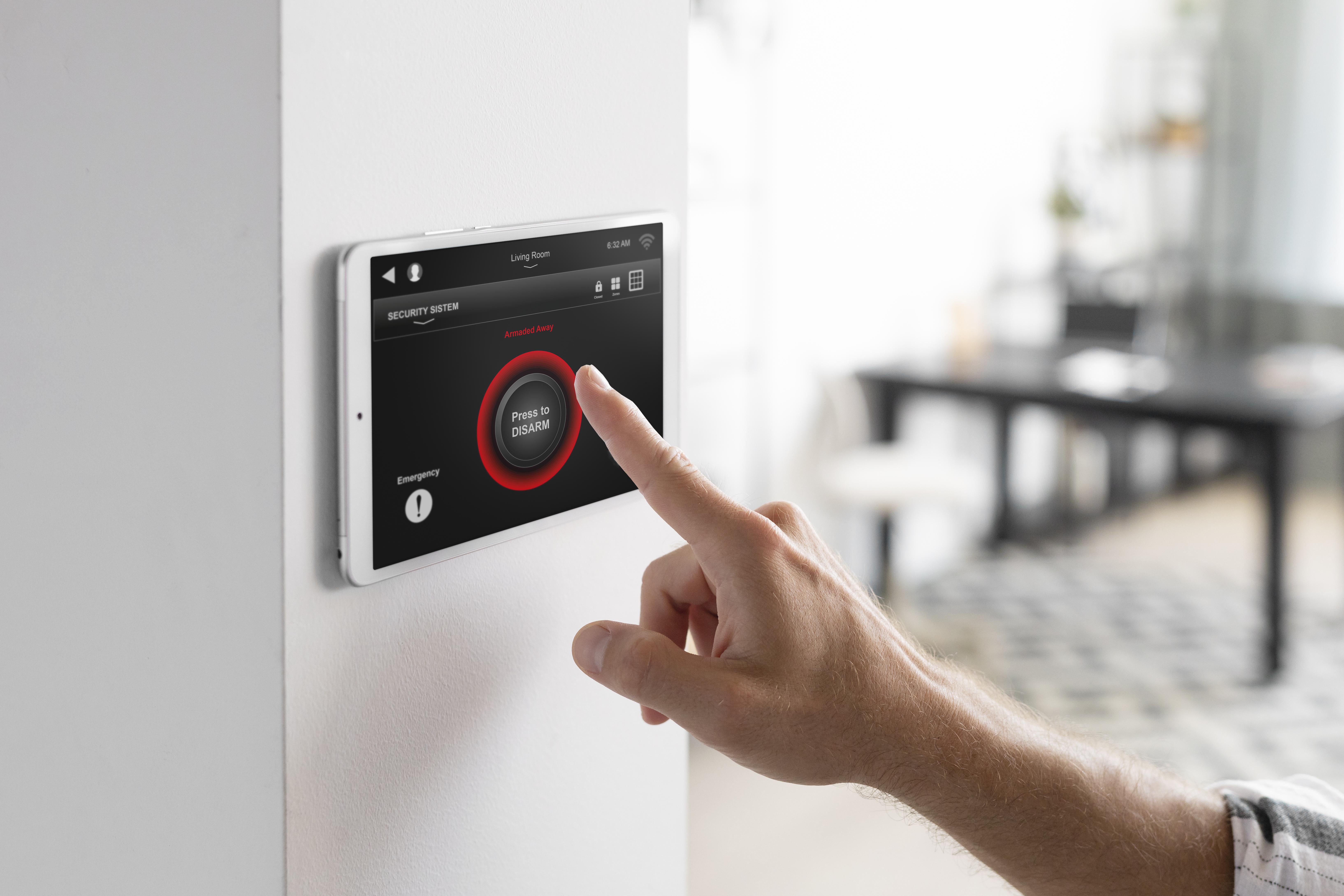 Person using smart home security control panel touchscreen inside modern house
