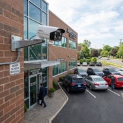 Commercial security camera monitoring the entrance and parking lot of an office building